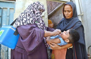 Health worker administering polio drops to a child.