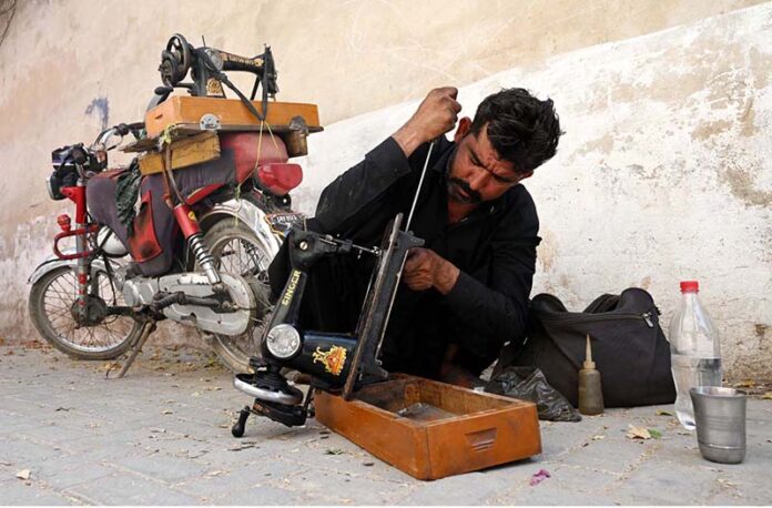 A mechanic busy in repairing a sewing machine in a street near Khaliq Colony