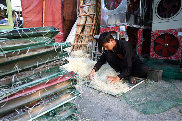 A worker busy in preparing (khas) to be used in air cooler at his workplace in the Provincial Capital