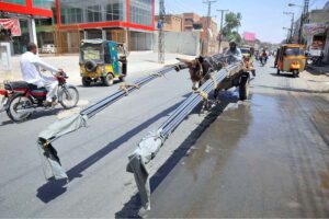 A donkey cart loaded with long iron bars makes its way toward the destination in the city