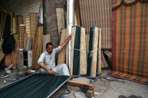 A worker busy in preparing (khas) to be used in air cooler at his workplace in the Provincial Capital