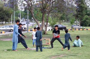 Children are playing 'bandar killa" a Punjabi traditional game in the green belt in the federal capital