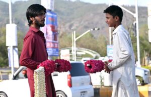 A vendor displays and sells flower garlands at a roadside in the Federal Capital, aiming to attract customers with the vibrant and fragrant offerings.