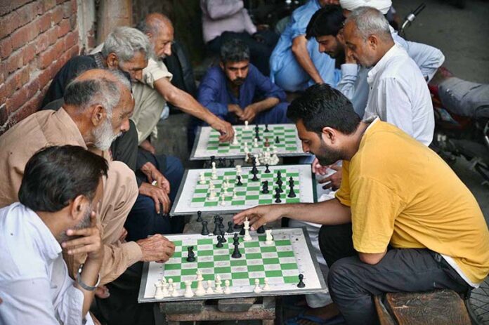 Locals enjoy a game of chess on the roadside near Lakshami Chowk during the pleasant evening in the provincial capital