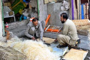 Workers use wood wool to make Aspen cooling pads for traditional air room coolers at his workplace in the provincial capital