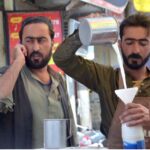 A street vendor sells buttermilk (lassi) to customers to beat the summer heat as the mercury rises in the city