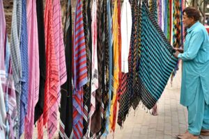 A man selecting and purchasing the men’s head scarf (Romaal) to protect themselves from hot weather on the roadside vendor in the Provincial Capital.