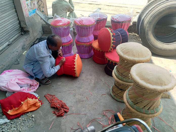A laborer sits in the shade near Shahdara Road making a set of wooden chairs made from bamboo sticks