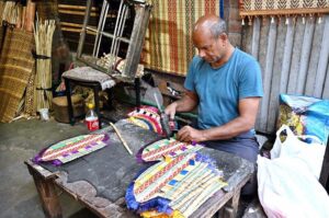A worker busy in preparing the handmade wooden fan to the customers at his shop.