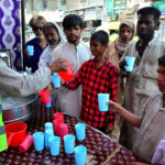 Volunteer giving the cold water to thirsty people at heatstroke relief camp organized by sohni dharti youth council at Hyder chowk during heat wave in the city
