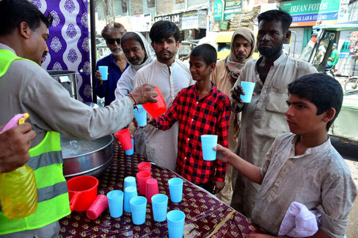 Volunteer giving the cold water to thirsty people at heatstroke relief camp organized by sohni dharti youth council at Hyder chowk during heat wave in the city