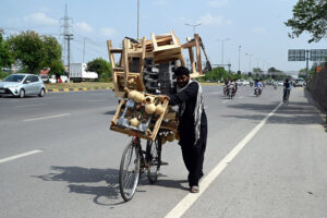 A vendor with a bicycle loaded with household items shuttles along the Expressway in the Federal Capital