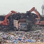 Heavy machinery being use for clear a large pile of garbage from garbage yard near fruit and vegetable market in federal capital