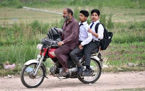 Students on their way to school on motorcycle as educational institutions reopen after a one-day closure due to Indian airstrikes