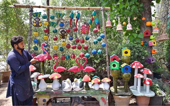 A vendor displays clay made pots and crafted artificial bird nests for garden décor to attract customers at H-9 Nursery
