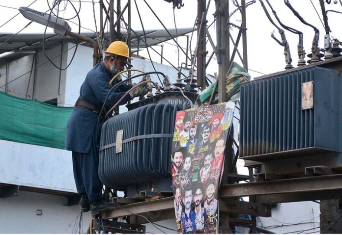 A WAPDA staffer busy in repairing power transformer at Jhumra Road