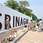 CDA workers fixing national flags on flyover at Srinagar Highway in the Federal Capital