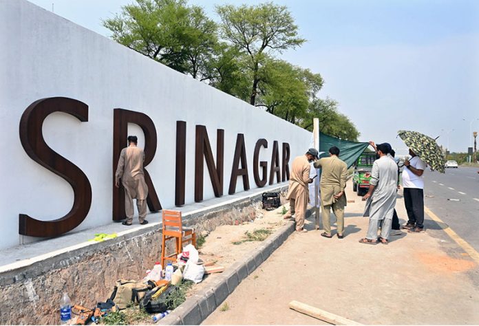 CDA workers fixing national flags on flyover at Srinagar Highway in the Federal Capital