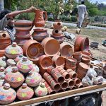 A vendor arranging and displaying clay made pots on his handcart to attract the customers in the Federal Capital