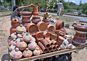 A vendor arranging and displaying clay made pots on his handcart to attract the customers in the Federal Capital