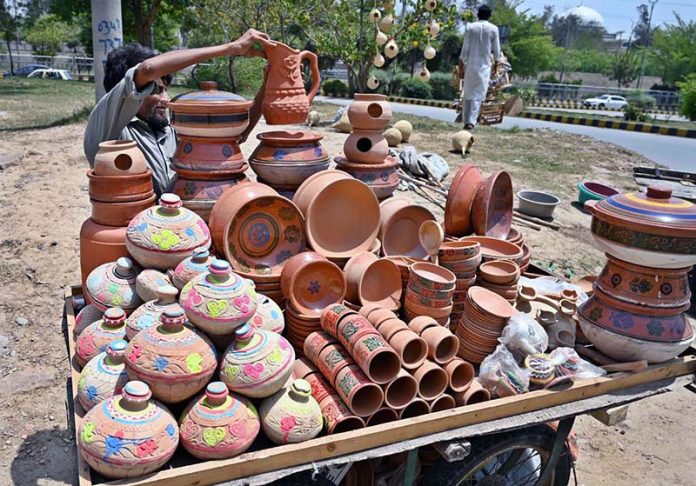 A vendor arranging and displaying clay made pots on his handcart to attract the customers in the Federal Capital