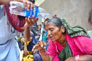 A person pours water on a woman's head during hot day in the city.