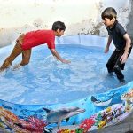 Children are taking bath in plastic pool to get some relief from hot weather in the city