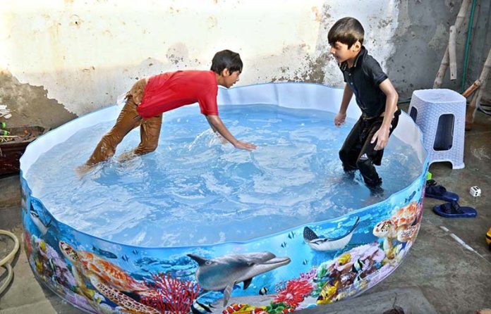 Children are taking bath in plastic pool to get some relief from hot weather in the city