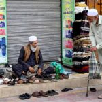 An elderly cobbler busy with his routine work on a roadside footpath in the city