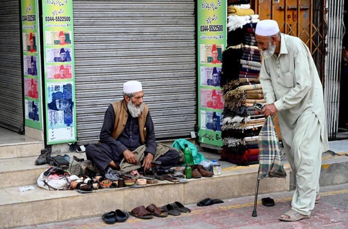 An elderly cobbler busy with his routine work on a roadside footpath in the city