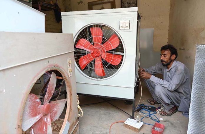 An electrician fixes a room cooler as demand rises with the arrival of summer in the city