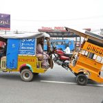 A person sitting on an auto rickshaw while holding an out of order tricycle at Khayyam Chowk