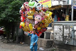 Young vendor selling colorful balloons to attract customers while shuttling on road in the Federal Capital