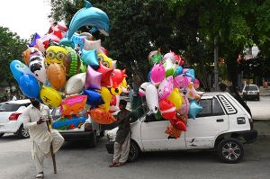 Young vendor selling colorful balloons to attract customers while shuttling on road in the Federal Capital