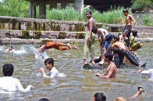 A large number of youngsters swimming in Rawal Lake spillway water to get some relief from hot weather in Federal Capital.
