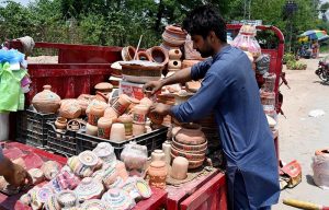 A vendor arranging and displaying clay made pots at his setup in the Federal Capital