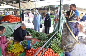 People purchasing fruits from a stall at weekly Sunday Bazaar, Peshawar Morr in Federal Capital.