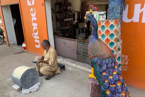 A craftsman makes beautiful models of peacocks at his workplace in the federal capital