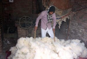 A worker is busy preparing cotton for filling quilts at his workplace