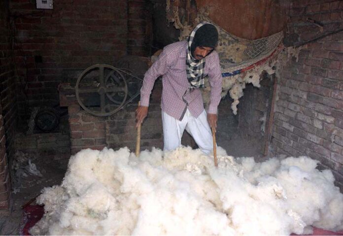 A worker is busy preparing cotton for filling quilts at his workplace