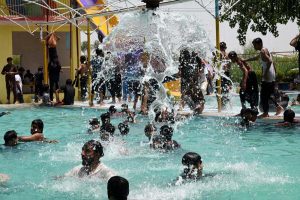 Youngsters bathing in a swimming pool to get relief from scorching hot weather in City.