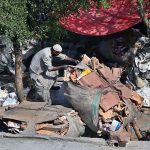 A laborer is busy collecting cardboard from roadside garbage