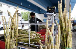 A vendor extracting sugarcane juice for customers at his roadside setup near Sheikh Zaid Hospital, The demand for sugarcane juice increases due to the intense heat