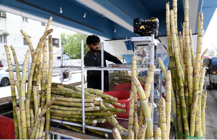 A vendor extracting sugarcane juice for customers at his roadside setup near Sheikh Zaid Hospital, The demand for sugarcane juice increases due to the intense heat