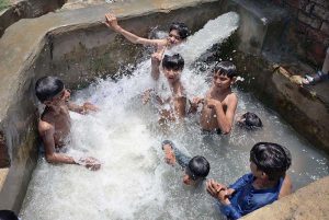 Youngster enjoying bathing in the running tube-well to get relief from scorching hot weather in the city.