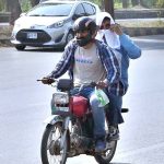 A motorcycle commuter covers his head with a wet towel to beat the heat, as PMD issues a public advisory amid an intense heatwave in the federal capital