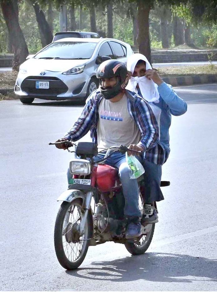 A motorcycle commuter covers his head with a wet towel to beat the heat, as PMD issues a public advisory amid an intense heatwave in the federal capital
