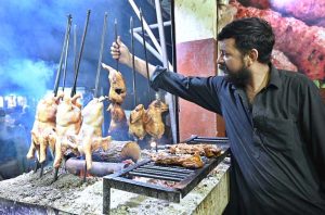 A vendor prepares Balochi chicken Sajji over coal at Chowk Rustam Park.