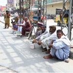Workers sitting on the roadside at Gol Chowk wait for potential customers to hire them for daily labor work