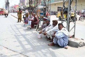 Workers sitting on the roadside at Gol Chowk wait for potential customers to hire them for daily labor work